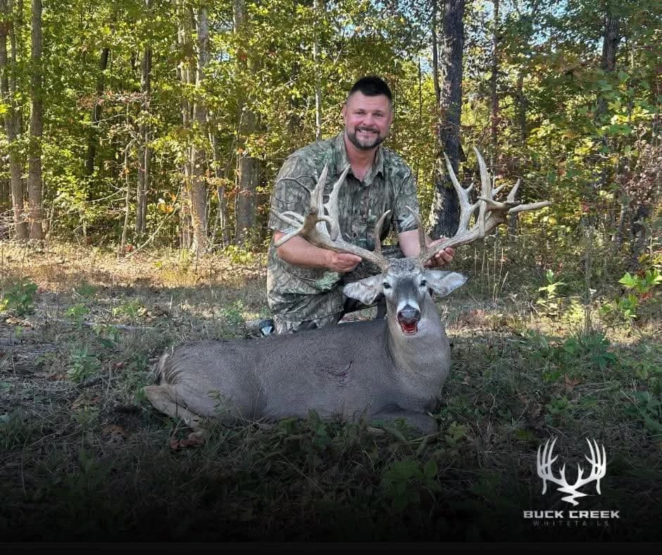 Hunter and a trophy whitetail at the edge of the woods